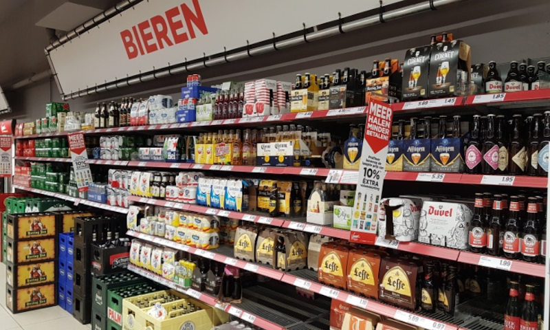 Bier schap in de supermarkt met kratten, sixpacks en flesjes bier